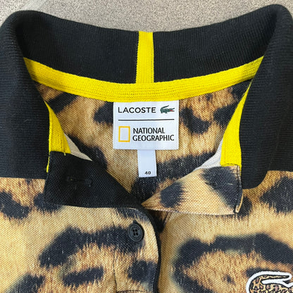 Lacoste x National Geographic AW20 Leopard Polo features an all-over beige, brown and black leopard print pattern across the fabric. The polo has black collar and sleeve hems, with a chest patch featuring the Lacoste crocodile logo in matching pattern colors.