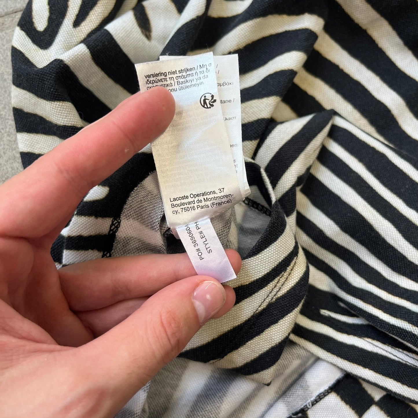  Lacoste x National Geographic AW20 Zebra Polo features an all-over white and black zebra print pattern across the fabric. The polo has black collar and sleeve hems, with a chest patch featuring the Lacoste crocodile logo in matching pattern colors.