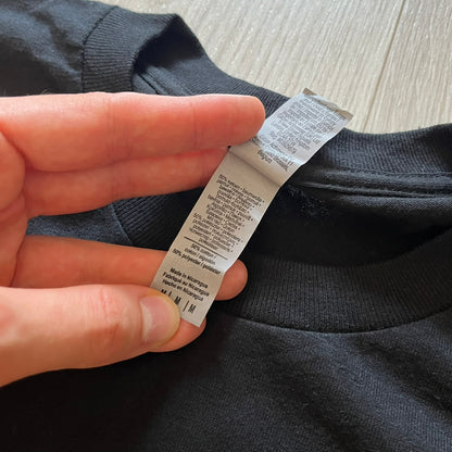 Hand holding a clothing label on a dark fabric background