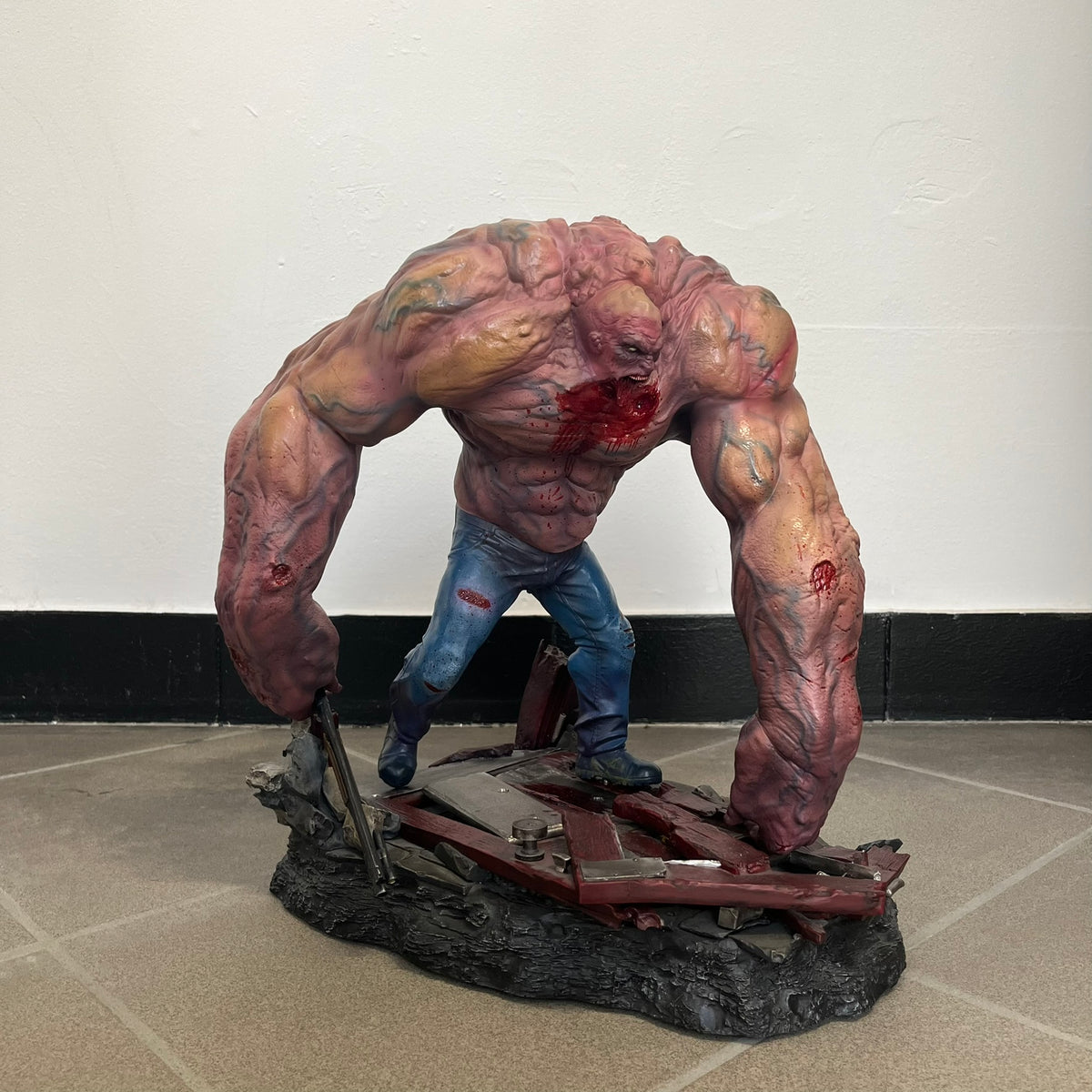 Left 4 Dead 2: Tank 2011 Exclusive Gaming Heads Statue is a limited edition poly-stone collectible based on the Tank character from Left 4 Dead 2. The statue is hand finished and hand painted, depicting the Tank smashing through a reinforced door with glow-in-the-dark painted eyes. It measures approximately 15 inches tall including the base and was limited to 300 pieces worldwide. This exclusive version comes with additional to scale Pump Shotgun that wasn't added in the standard edition. This piece is numb