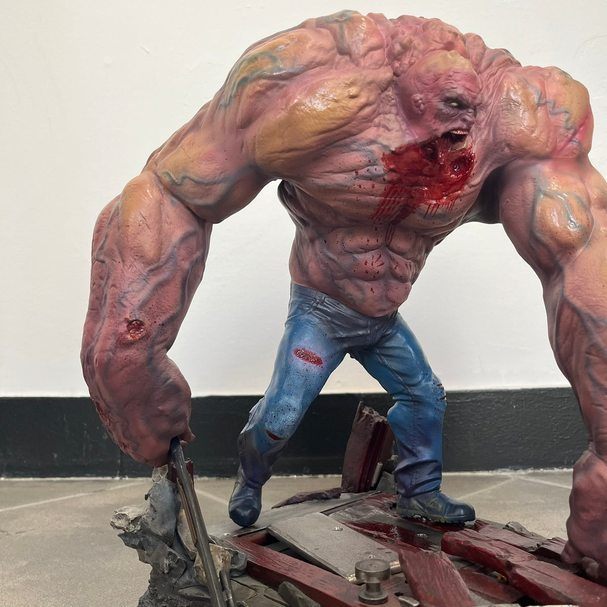 Left 4 Dead 2: Tank 2011 Exclusive Gaming Heads Statue is a limited edition poly-stone collectible based on the Tank character from Left 4 Dead 2. The statue is hand finished and hand painted, depicting the Tank smashing through a reinforced door with glow-in-the-dark painted eyes. It measures approximately 15 inches tall including the base and was limited to 300 pieces worldwide. This exclusive version comes with additional to scale Pump Shotgun that wasn't added in the standard edition. This piece is numb