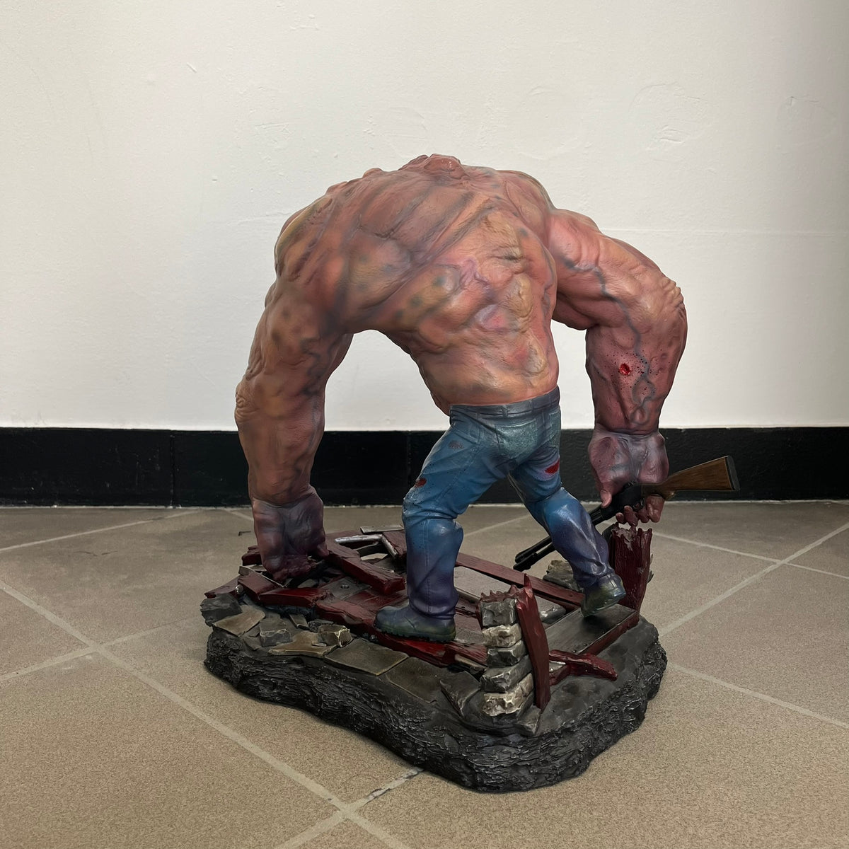 Left 4 Dead 2: Tank 2011 Exclusive Gaming Heads Statue is a limited edition poly-stone collectible based on the Tank character from Left 4 Dead 2. The statue is hand finished and hand painted, depicting the Tank smashing through a reinforced door with glow-in-the-dark painted eyes. It measures approximately 15 inches tall including the base and was limited to 300 pieces worldwide. This exclusive version comes with additional to scale Pump Shotgun that wasn't added in the standard edition. This piece is numb