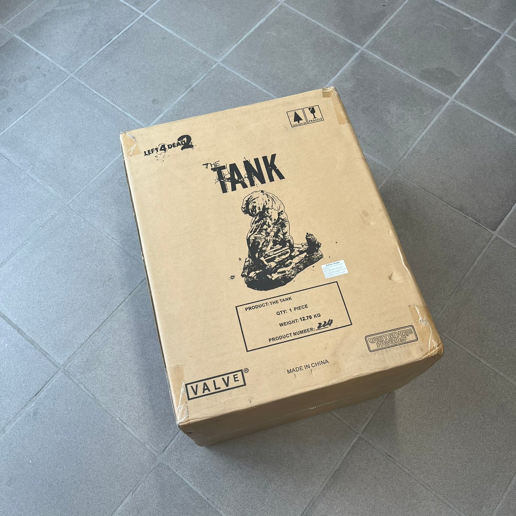 Left 4 Dead 2 Tank 2011 Gaming Heads Statue is a limited edition poly-stone collectible based on the Tank character from Left 4 Dead 2. The statue is hand finished and hand painted, depicting the Tank smashing through a reinforced door with glow-in-the-dark painted eyes. It measures approximately 15 inches tall including the base and was limited to 750 pieces worldwide. This piece is number 224 and comes with the original shipping box, styrofoam packaging, colored box, and identification/validation card.
