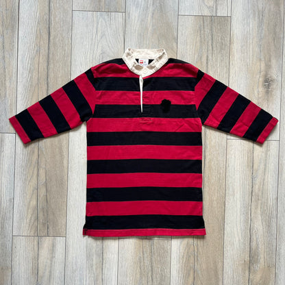 LEGO 2000 Black &amp; Red Rugby Shirt is a black and red striped long-sleeve rugby shirt with a cream/white collar. The chest includes a black Velcro patch panel without an attached patch, and a small LEGO tag is placed on one of the sleeves. The shirt has an official LEGO 2000 licensed neck tag.