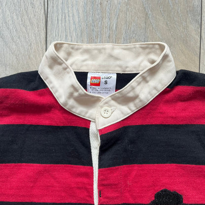 LEGO 2000 Black &amp; Red Rugby Shirt is a black and red striped long-sleeve rugby shirt with a cream/white collar. The chest includes a black Velcro patch panel without an attached patch, and a small LEGO tag is placed on one of the sleeves. The shirt has an official LEGO 2000 licensed neck tag.
