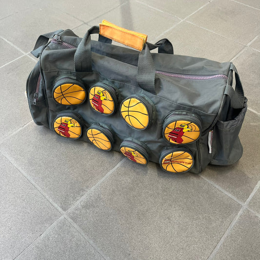 Lego Basketball 2003 Multi Pocket Gray Bag is a gray gym bag with orange side panels and an orange strap handle, featuring a Lego Sports tag. The front is designed to resemble a Lego 8x2 brick, with 8 zippable circular pockets featuring basketball orange graphics or basketball player designs.