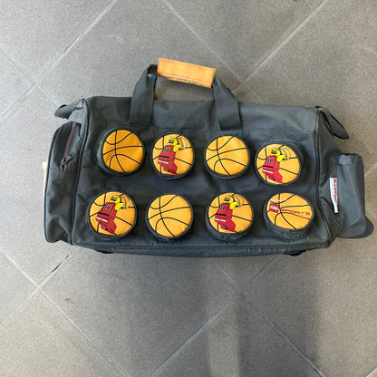 Lego Basketball 2003 Multi Pocket Gray Bag is a gray gym bag with orange side panels and an orange strap handle, featuring a Lego Sports tag. The front is designed to resemble a Lego 8x2 brick, with 8 zippable circular pockets featuring basketball orange graphics or basketball player designs.