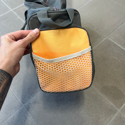 Lego Basketball 2003 Multi Pocket Gray Bag is a gray gym bag with orange side panels and an orange strap handle, featuring a Lego Sports tag. The front is designed to resemble a Lego 8x2 brick, with 8 zippable circular pockets featuring basketball orange graphics or basketball player designs.