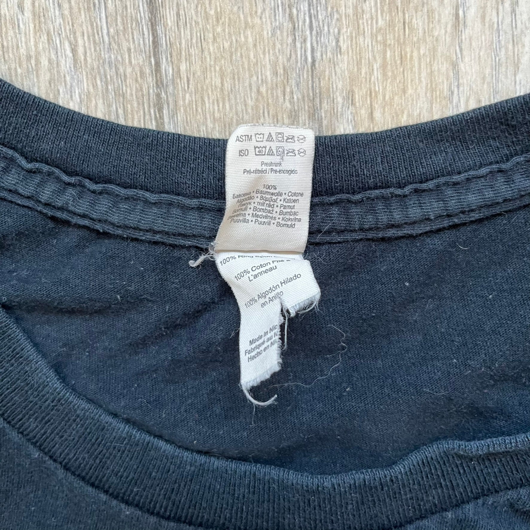 Lego Batman 3: Beyond Gotham 2014 Tee is a black T-shirt made on an Anvil blank. The front features a graphic of Batman in a white and blue suit standing on the moon, holding a Lego flag, with a planet and space station in the background. The back includes the “Batman 3: Beyond Gotham” logo and a Lego logo placed on the upper back area, with small licensing print beneath.