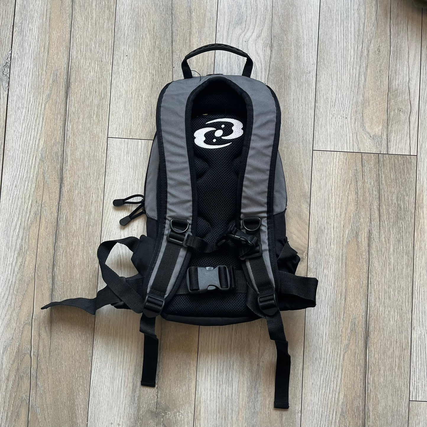 Lego Bionicle 2000s Matoran Alphabet Backpack is a backpack featuring a front design spelling “Bionicle” using the Matoran alphabet. The bag includes two front exterior pockets, a main compartment with three internal pockets, and a top media port for headphones. Additional details include padded and vented back panel, adjustable shoulder straps with chest connector and waist strap, top handle, and elastic cross straps on the front for extra storage.
