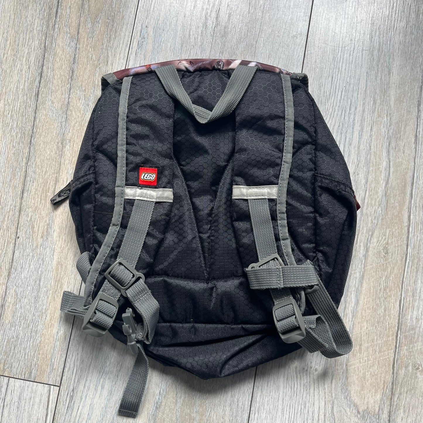 LEGO Bionicle 2009 Small Logo Backpack is a black backpack featuring a large white Bionicle logo on the lower front. The top flap section has a red all-over print with Bionicle characters and a LEGO logo patch. The interior includes a LEGO 2009 licensed tag.