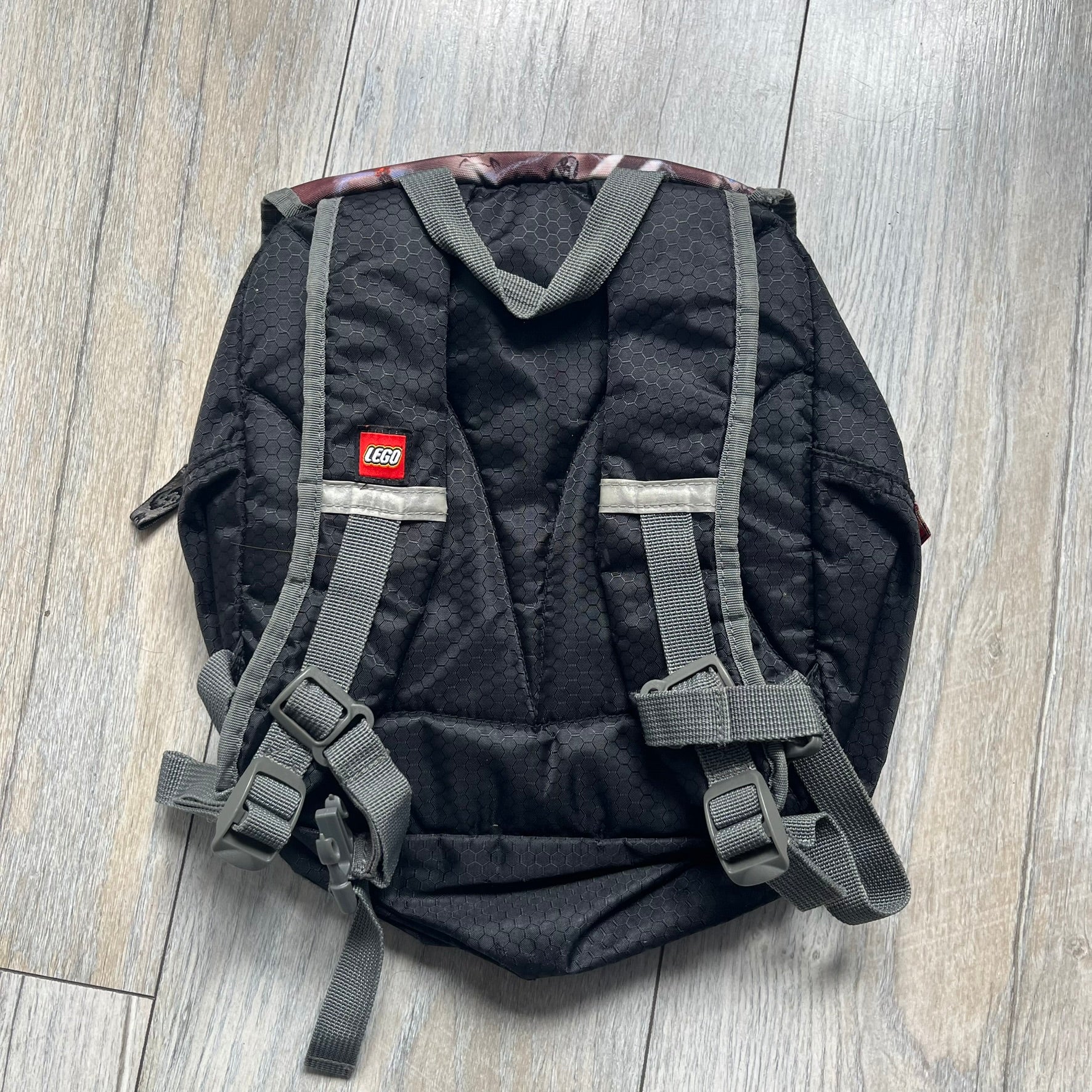 LEGO Bionicle 2009 Small Logo Backpack is a black backpack featuring a large white Bionicle logo on the lower front. The top flap section has a red all-over print with Bionicle characters and a LEGO logo patch. The interior includes a LEGO 2009 licensed tag.