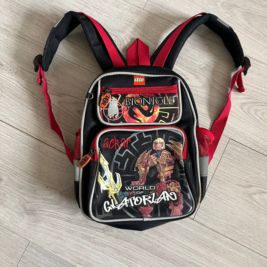Lego Bionicle 2010 Glatorian Gresh Backpack made by Class Investment in 2010, featuring a front pocket with an embroidered Glatorian Ackar figure and text. The top pocket includes both Bionicle and LEGO logos, along with custom rubber zipper pulls. Finished with two side bottle pockets and additional Bionicle logo details, making it a great rare collectible for fans of the series.