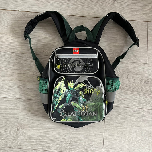 Lego Bionicle 2010 Glatorian Gresh Backpack made by Class Investment in 2010, featuring a front pocket with an embroidered Glatorian Gresh figure and text. The top pocket includes both Bionicle and LEGO logos, along with custom rubber zipper pulls. Finished with two side bottle pockets and additional Bionicle logo details, making it a great rare collectible for fans of the series.