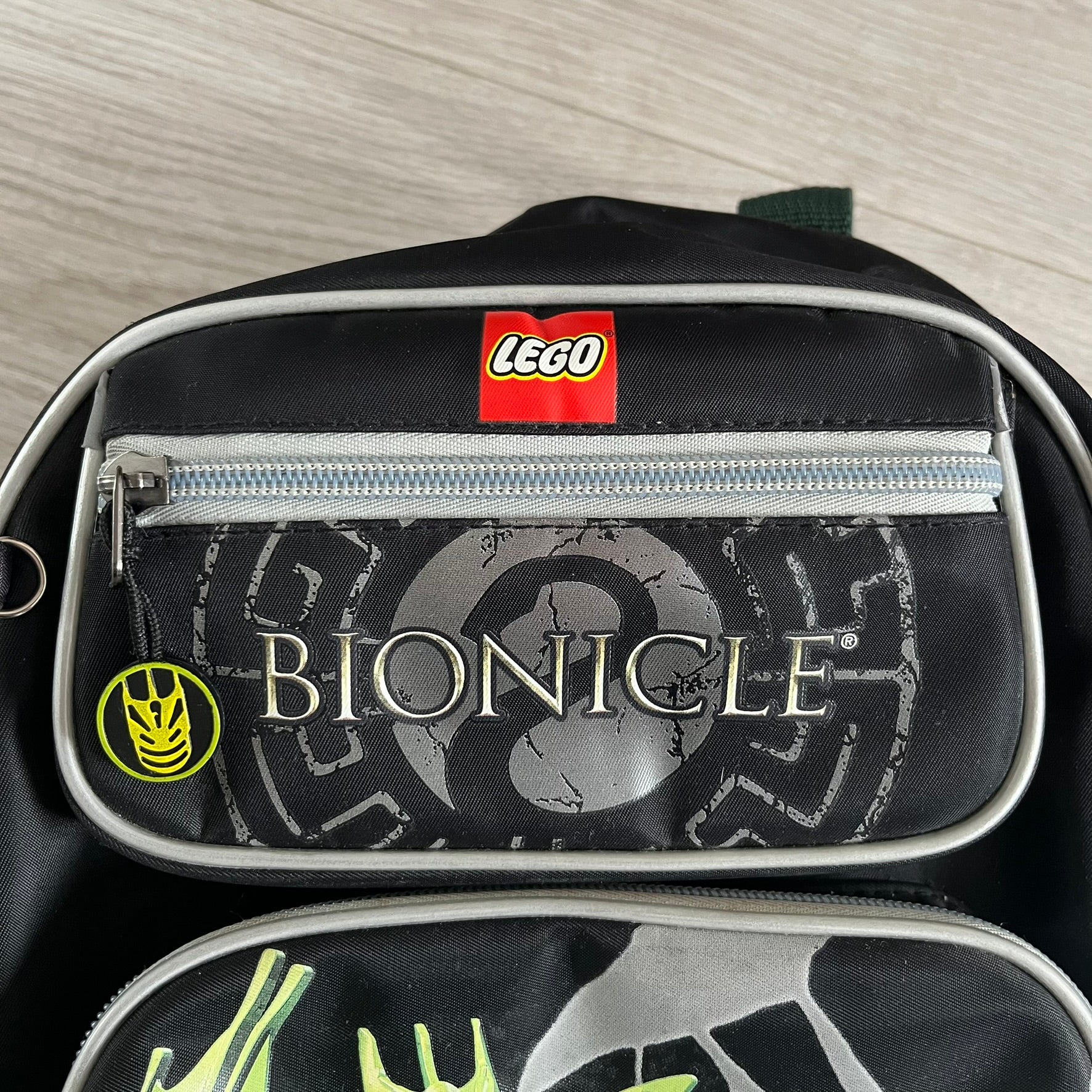Lego Bionicle 2010 Glatorian Gresh Backpack made by Class Investment in 2010, featuring a front pocket with an embroidered Glatorian Gresh figure and text. The top pocket includes both Bionicle and LEGO logos, along with custom rubber zipper pulls. Finished with two side bottle pockets and additional Bionicle logo details, making it a great rare collectible for fans of the series.