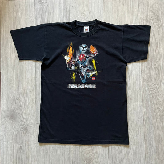 Rare 2000s Lego Bionicle T-shirt showcasing Toa Hordika Vakama from the 2005 set. Features the glowing Bionicle logo under the Binicle, small Lego branding and a naturally sunfaded black wash. A collectible tee that perfectly captures early-2000s nostalgia.