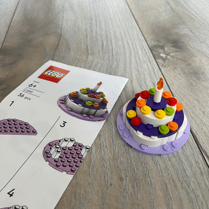 LEGO Cake Make and Take Build is a limited promotional LEGO set distributed as an exclusive “make & take” event and not available for retail purchase. The model features a small white and purple cake-style build with multicolor dot detailing and a single candle element on top.