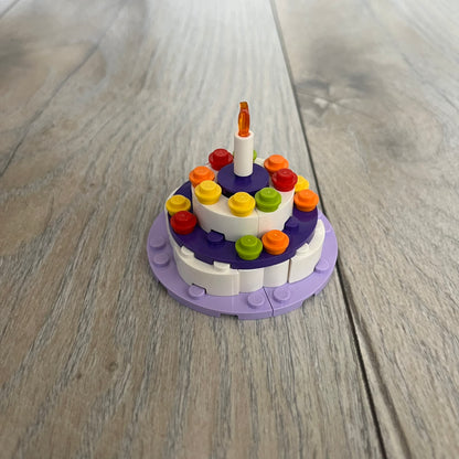 LEGO Cake Make and Take Build is a limited promotional LEGO set distributed as an exclusive “make & take” event and not available for retail purchase. The model features a small white and purple cake-style build with multicolor dot detailing and a single candle element on top.