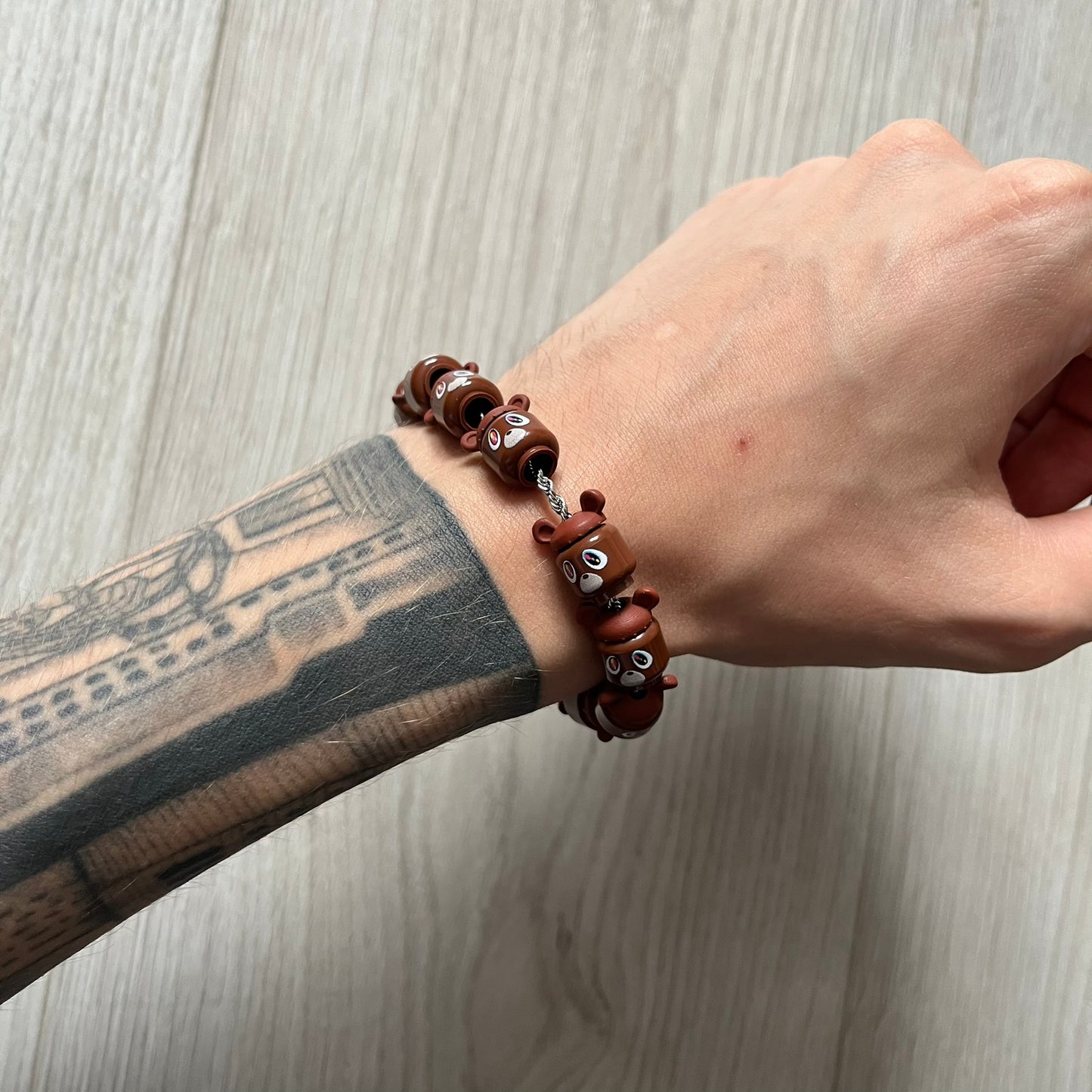 Lego Graduation Brick Bracelet featuring ten brown Lego bear heads from Kanye West’s Graduation era, set on a thin silver bracelet. The heads are standard Lego size and the piece comes in a custom-designed display box. Made by TheCanvasDon.