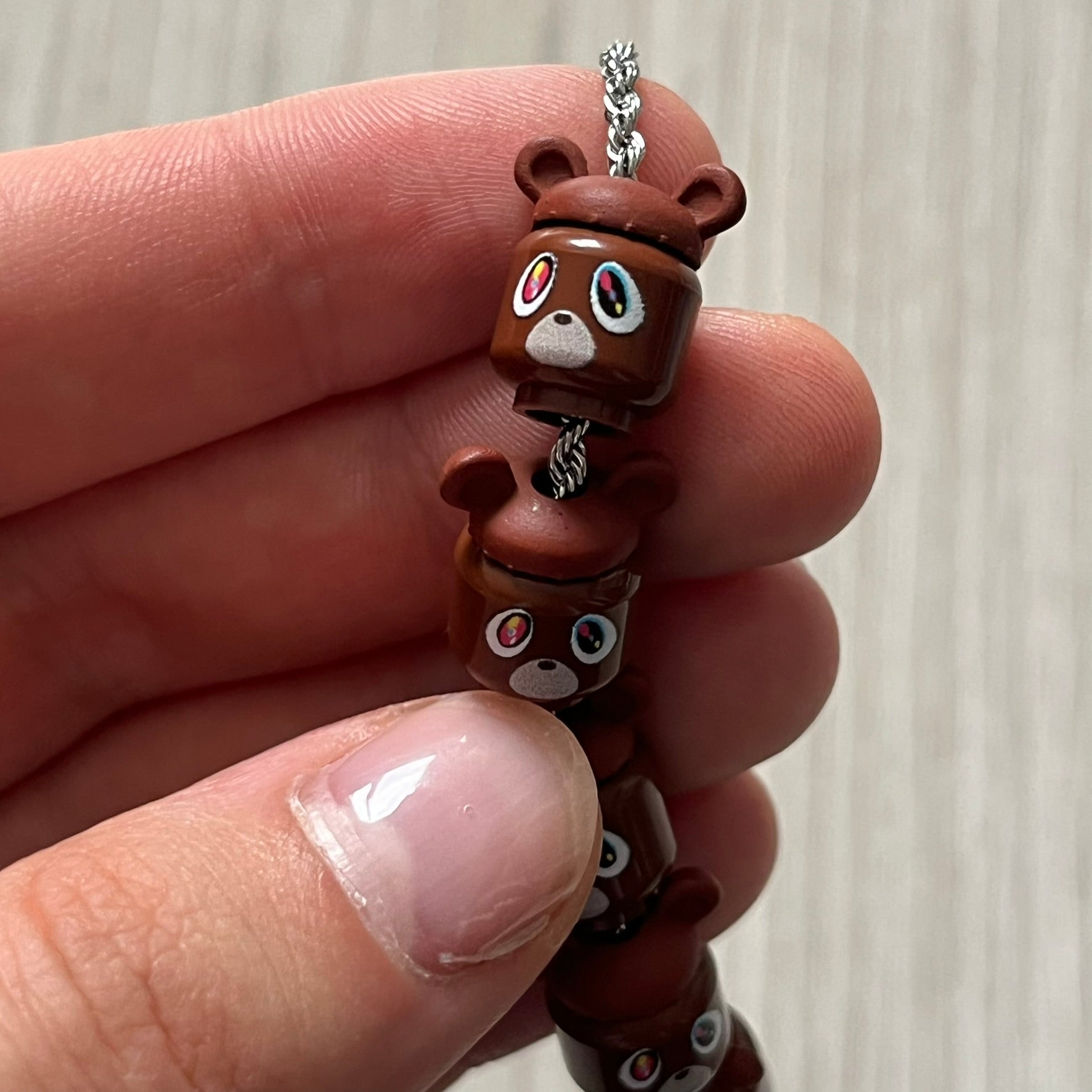 Lego Graduation Brick Bracelet featuring ten brown Lego bear heads from Kanye West’s Graduation era, set on a thin silver bracelet. The heads are standard Lego size and the piece comes in a custom-designed display box. Made by TheCanvasDon.