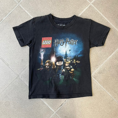 Lego Harry Potter: Years 1-4 Game 2011 Cover Tee is a black kids' T-shirt made from 100% cotton, featuring the game's cover artwork with classic characters and the Lego Harry Potter logo on the front. It carries a licensed 2011 Warner Bros. neck tag.