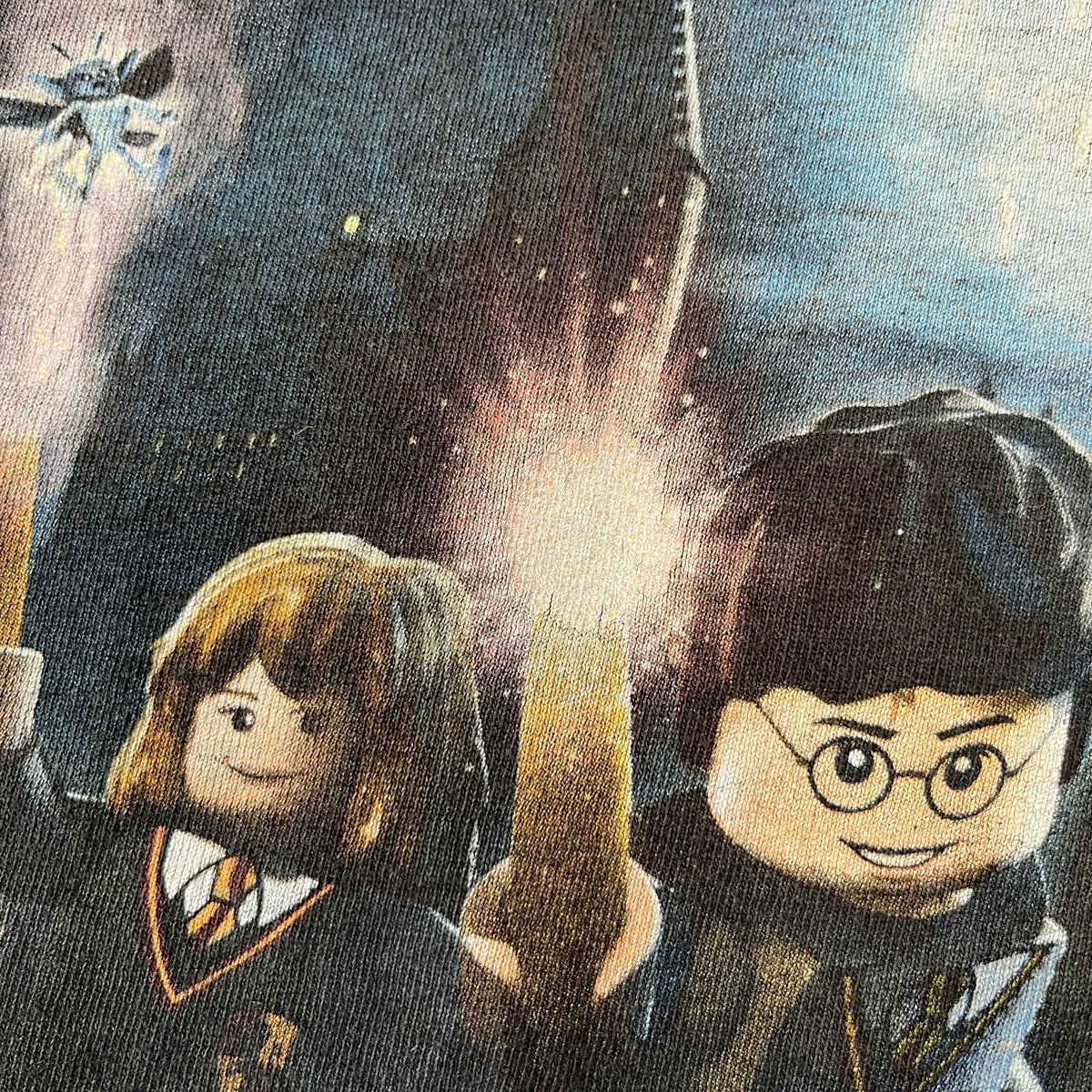 Lego Harry Potter: Years 1-4 Game 2011 Cover Tee is a black kids' T-shirt made from 100% cotton, featuring the game's cover artwork with classic characters and the Lego Harry Potter logo on the front. It carries a licensed 2011 Warner Bros. neck tag.