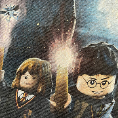 Lego Harry Potter: Years 1-4 Game 2011 Cover Tee is a black kids' T-shirt made from 100% cotton, featuring the game's cover artwork with classic characters and the Lego Harry Potter logo on the front. It carries a licensed 2011 Warner Bros. neck tag.