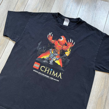 Lego Legends of Chima 2014 Black Tee is a black T-shirt made on a Gildan Ultra Cotton blank. The front features Winzar holding a torch with a large red character behind him and additional faded grey characters in the background. Below the graphic are the Lego Legends of Chima logo, “Official Lego Club Member” text, website link, and small 2014 licensing print.