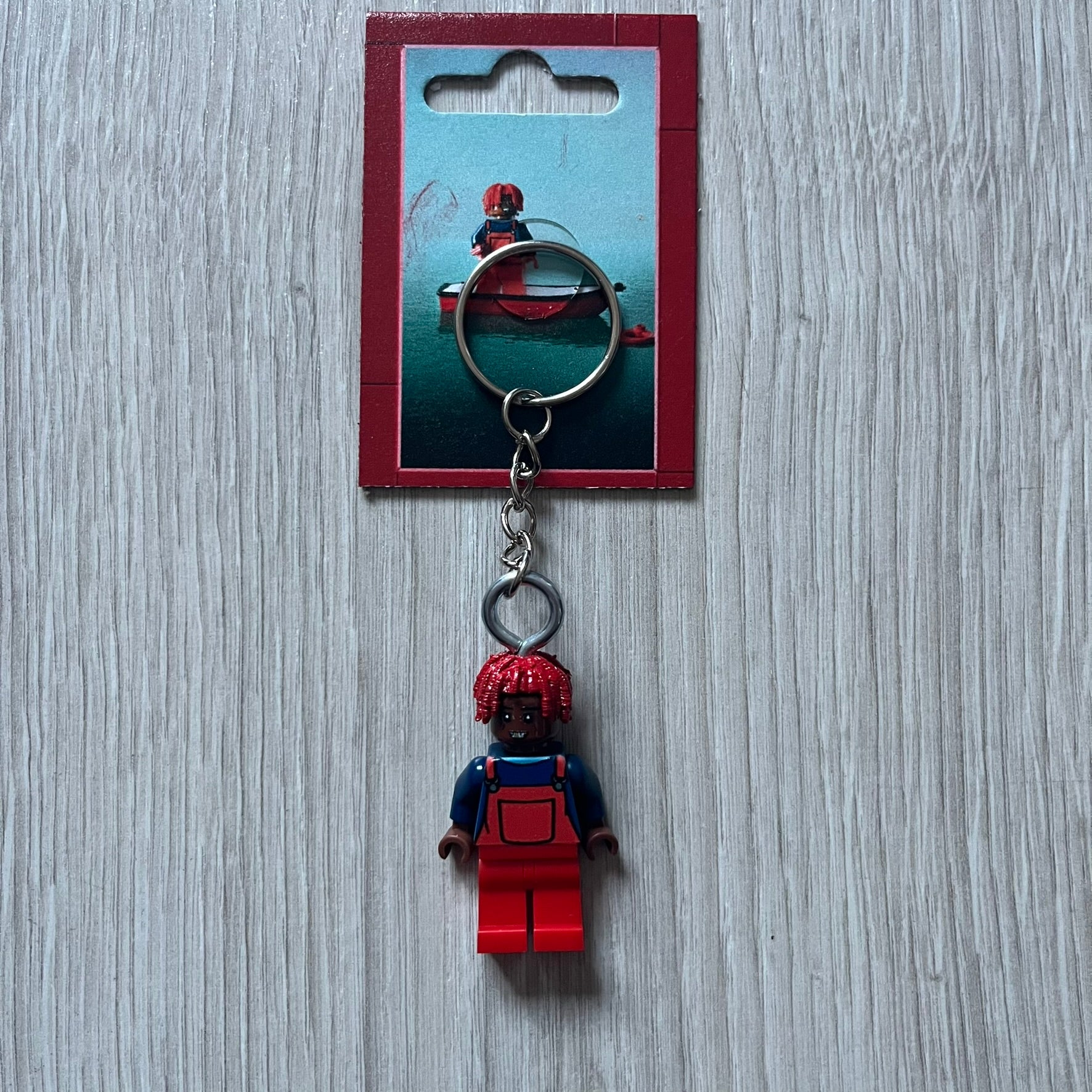 Lego Lil Yachty 'Lil Block' keychain featuring a custom Lego figure of Lil Yachty with red overalls and 3d red dreads. The figure is attached to a Lego-style recreation of the 2016 'Lil Boat' album cover, reimagined in brick graphics. A playful and creative collectible that merges music culture with fan-made Lego artistry, made by TheCanvasDon.