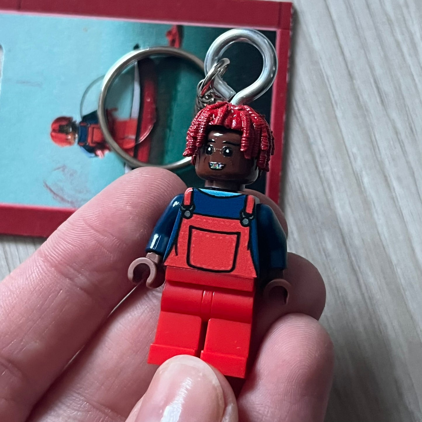 Lego Lil Yachty 'Lil Block' keychain featuring a custom Lego figure of Lil Yachty with red overalls and 3d red dreads. The figure is attached to a Lego-style recreation of the 2016 'Lil Boat' album cover, reimagined in brick graphics. A playful and creative collectible that merges music culture with fan-made Lego artistry, made by TheCanvasDon.