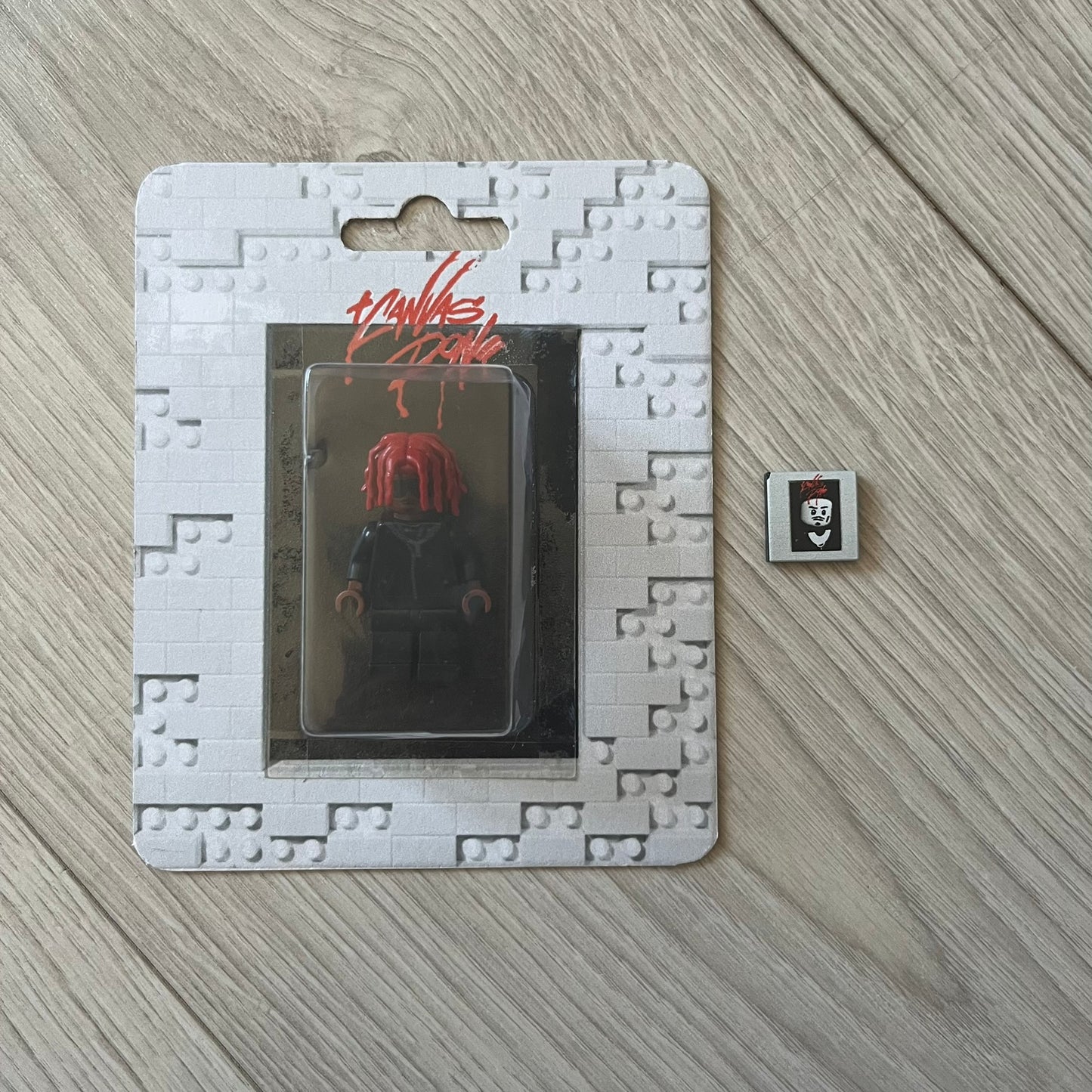 Lego Playboi Carti “Whole Lotta Red” minifigure featuring the Carti with red dreads from the album era. The figure is displayed on a paper/cartboard display accompanied by a small plate of the Lego style album cover, a limited addition only for first orders. A collectible piece from TheCanvasDon.