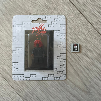 Lego Playboi Carti “Whole Lotta Red” minifigure featuring the Carti with red dreads from the album era. The figure is displayed on a paper/cartboard display accompanied by a small plate of the Lego style album cover, a limited addition only for first orders. A collectible piece from TheCanvasDon.