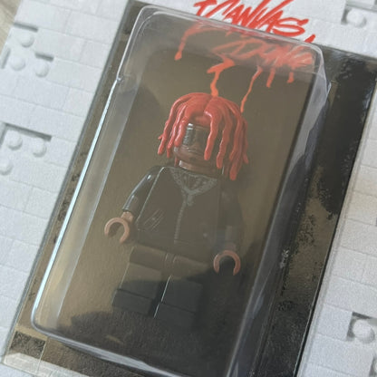Lego Playboi Carti “Whole Lotta Red” minifigure featuring the Carti with red dreads from the album era. The figure is displayed on a paper/cartboard display accompanied by a small plate of the Lego style album cover, a limited addition only for first orders. A collectible piece from TheCanvasDon.