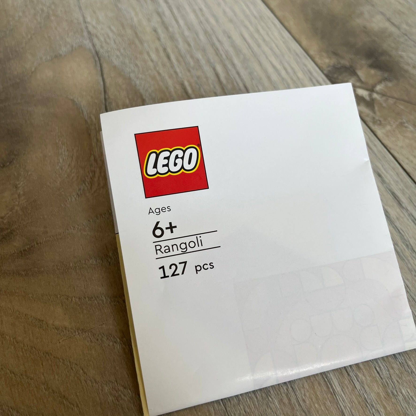LEGO Rangoli Make and Take Build is a limited promotional LEGO set distributed as an exclusive “make & take” event and not available for retail purchase. The model features three small square rangoli-style builds arranged in decorative patterns. The designs use combinations of yellow, orange, red, brown, blue, and pink elements, with the first and third patterns matching each other.