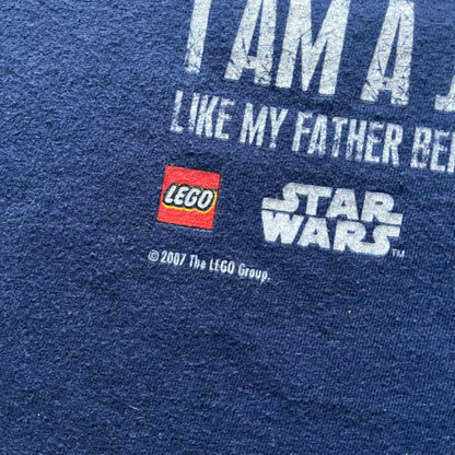 Vintage 2007 Lego Star Wars tee featuring Luke Skywalker with a lightsaber and the quote “I am a Jedi like my father before me.” Small Lego Star Wars logo sits underneath the graphic. Printed on a classic navy Fruit of the Loom blank perfect for collectors and SW fans.
