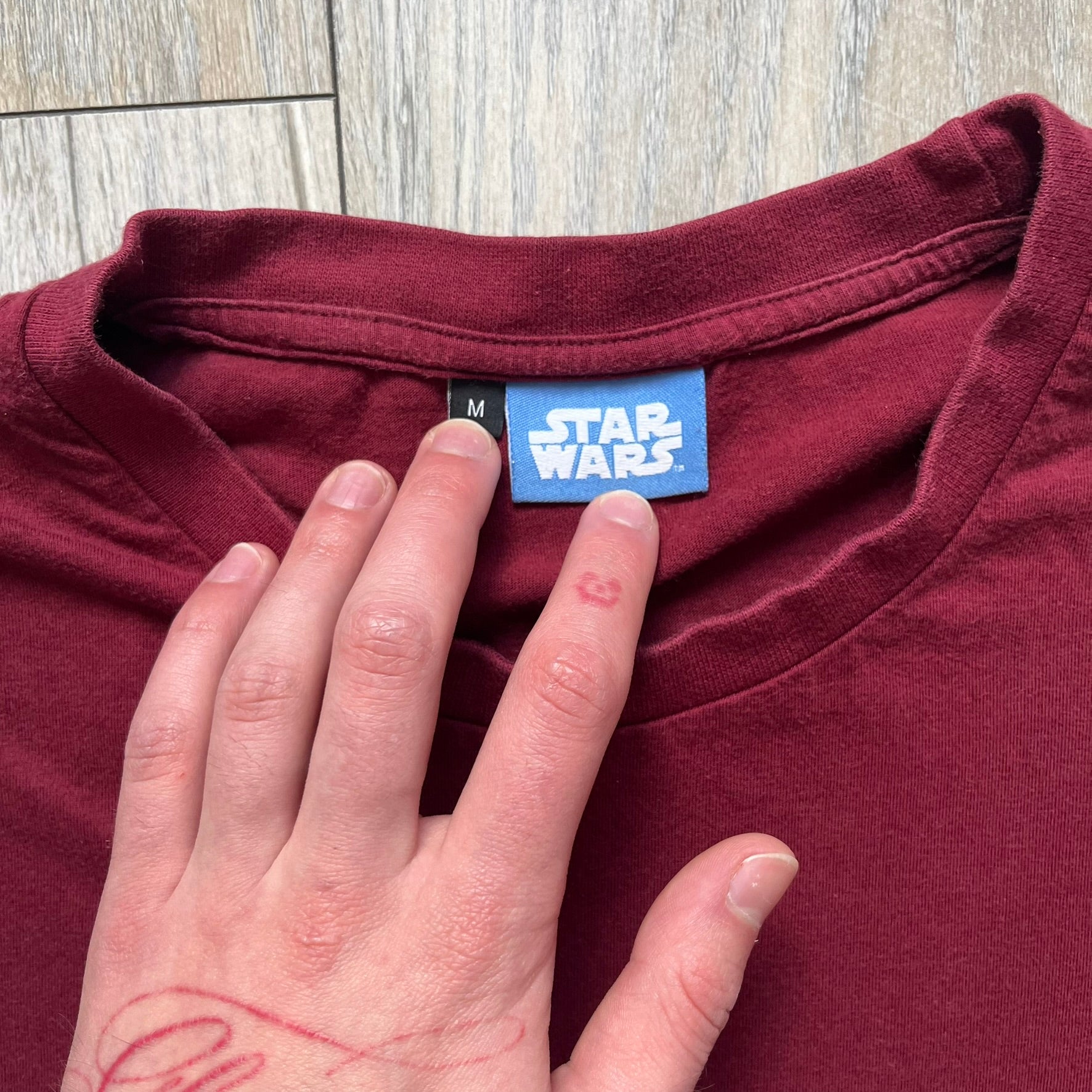 This Lego Star Wars 2008 Jedi Tee (Medium) in burgundy showcases Luke Skywalker wielding a blue lightsaber with a 'cracked' “I Am a Jedi” text. Officially licensed by Lego Star Wars, the tee includes authentic 2008 branding under the Luke minifigure graphic.
