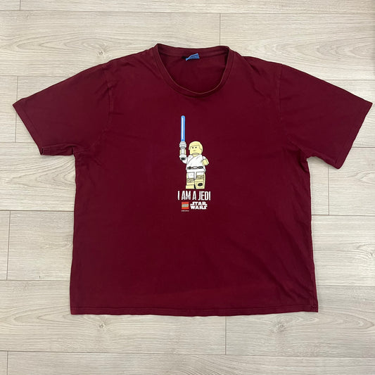 This Lego Star Wars 2008 Jedi Tee (XXXL) in burgundy showcases Luke Skywalker wielding a blue lightsaber with a 'cracked' “I Am a Jedi” text. Officially licensed by Lego Star Wars, the tee includes authentic 2008 branding under the Luke minifigure graphic.