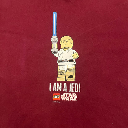This Lego Star Wars 2008 Jedi Tee (XXXL) in burgundy showcases Luke Skywalker wielding a blue lightsaber with a 'cracked' “I Am a Jedi” text. Officially licensed by Lego Star Wars, the tee includes authentic 2008 branding under the Luke minifigure graphic.