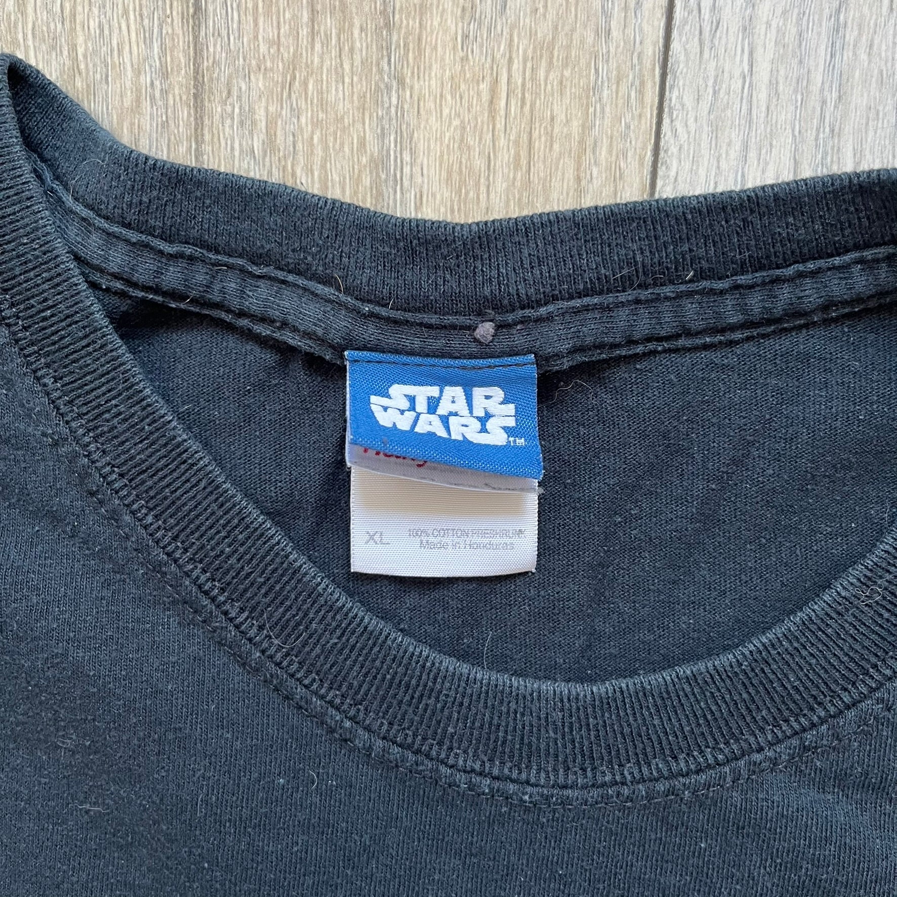 Lego Star Wars 2010 Stormtrooper Tee is a black T-shirt featuring a front graphic of a Lego Stormtrooper holding a blaster against an orange background. Below the graphic is the text “These aren’t the droids we’re looking for…” along with the Lego Star Wars logo and small 2010 licensing print.
