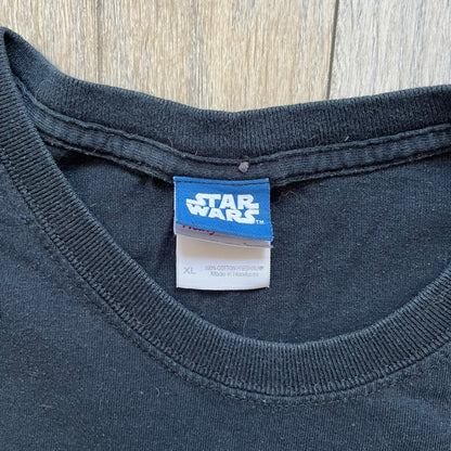 Lego Star Wars 2010 Stormtrooper Tee is a black T-shirt featuring a front graphic of a Lego Stormtrooper holding a blaster against an orange background. Below the graphic is the text “These aren’t the droids we’re looking for…” along with the Lego Star Wars logo and small 2010 licensing print.