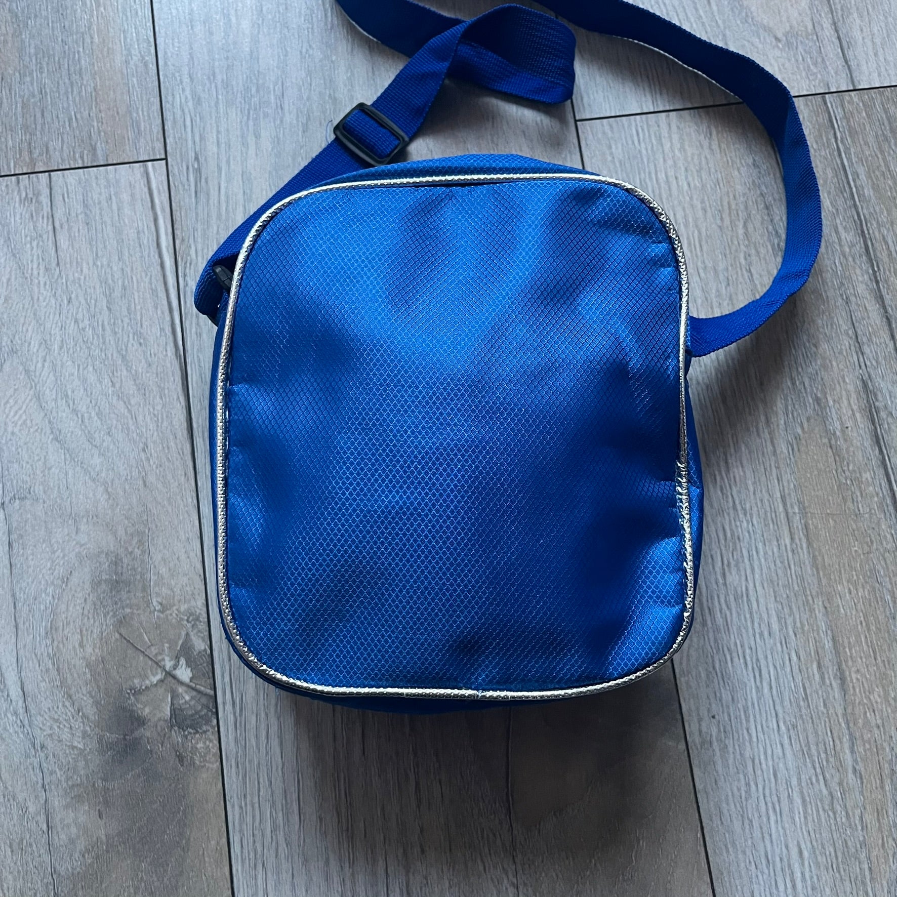 Lego Star Wars III: The Clone Wars Shoulder Bag is a blue shoulder bag featuring a raised 3D front graphic panel (not printed) with Lego Star Wars artwork. The design shows Obi-Wan Kenobi, Anakin Skywalker, and Yoda with lightsabers on a battlefield scene, with clone troopers, Ahsoka Tano, and General Grievous in the background.