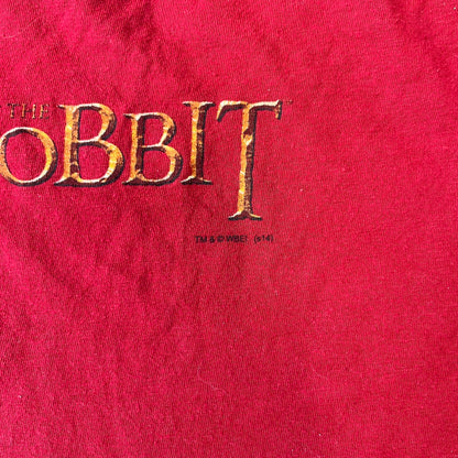 Lego The Hobbit 2014 Press Kit Red Tee features a red T-shirt with a full-front graphic designed to resemble Bilbo Baggins’ outfit in LEGO form, including a green undershirt, beige tie, and dark details. The upper back has a LEGO The Hobbit logo with 2014 licensing text. Originally included as part of a press kit with additional items.