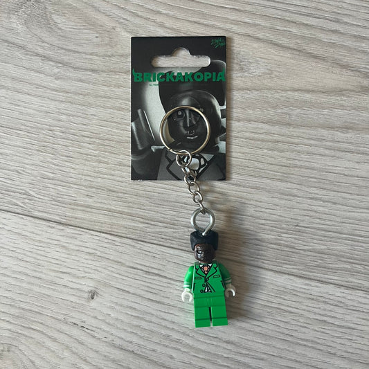 Lego x Tyler, the Creator “Brickakopia” keychain featuring a custom Lego figure of Tyler in a green suit. The figure is attached to a Lego-style recreation of the 2024 Chromakopia album cover, reimagined in brick graphics. A playful and creative collectible that merges music culture with fan-made Lego artistry, made by TheCanvasDon.