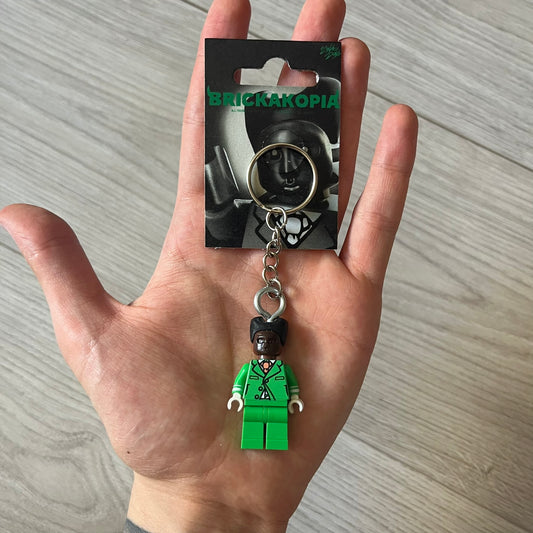 Lego x Tyler, the Creator “Brickakopia” keychain featuring a custom Lego figure of Tyler in a green suit. The figure is attached to a Lego-style recreation of the 2024 Chromakopia album cover, reimagined in brick graphics. A playful and creative collectible that merges music culture with fan-made Lego artistry, made by TheCanvasDon.