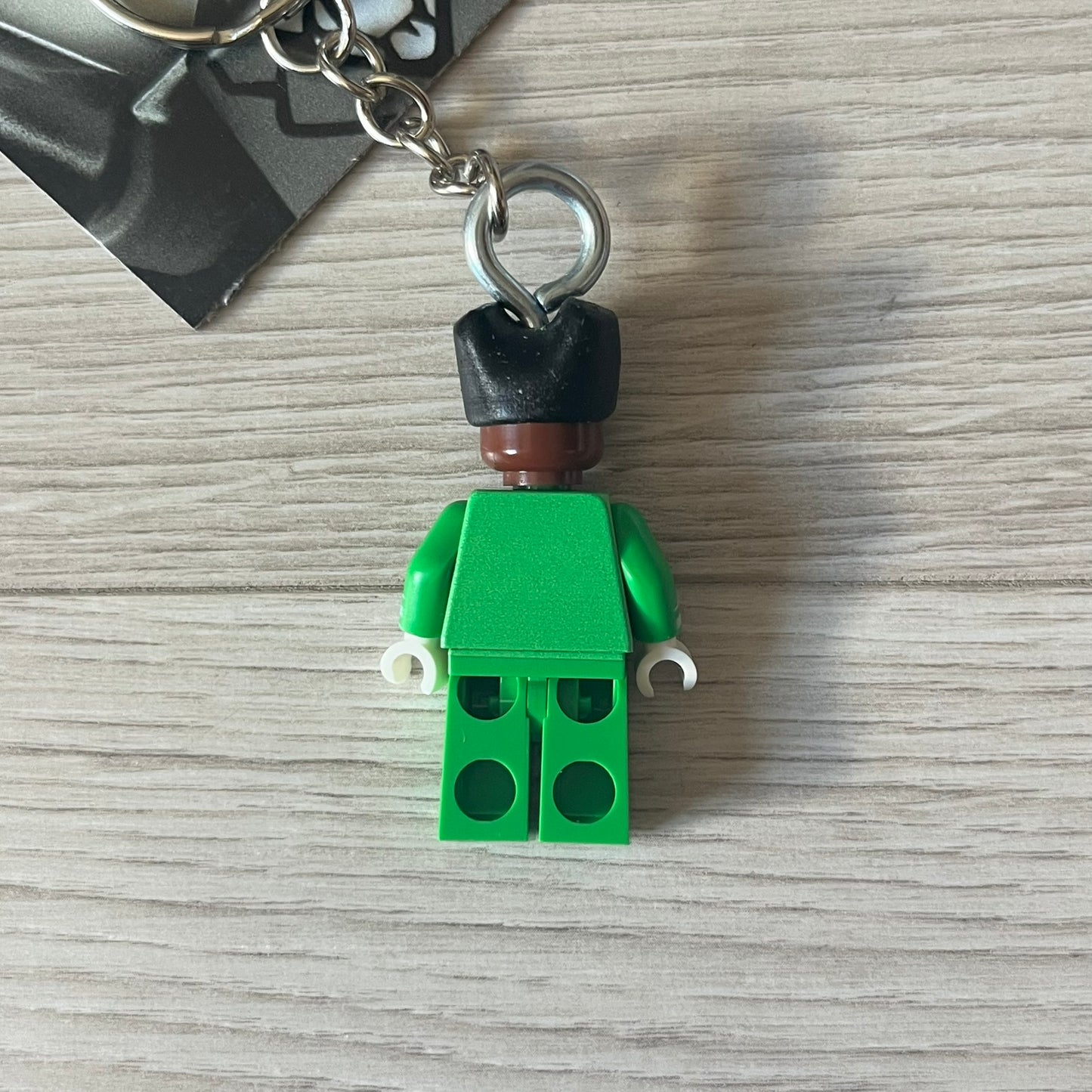 Lego x Tyler, the Creator “Brickakopia” keychain featuring a custom Lego figure of Tyler in a green suit. The figure is attached to a Lego-style recreation of the 2024 Chromakopia album cover, reimagined in brick graphics. A playful and creative collectible that merges music culture with fan-made Lego artistry, made by TheCanvasDon.