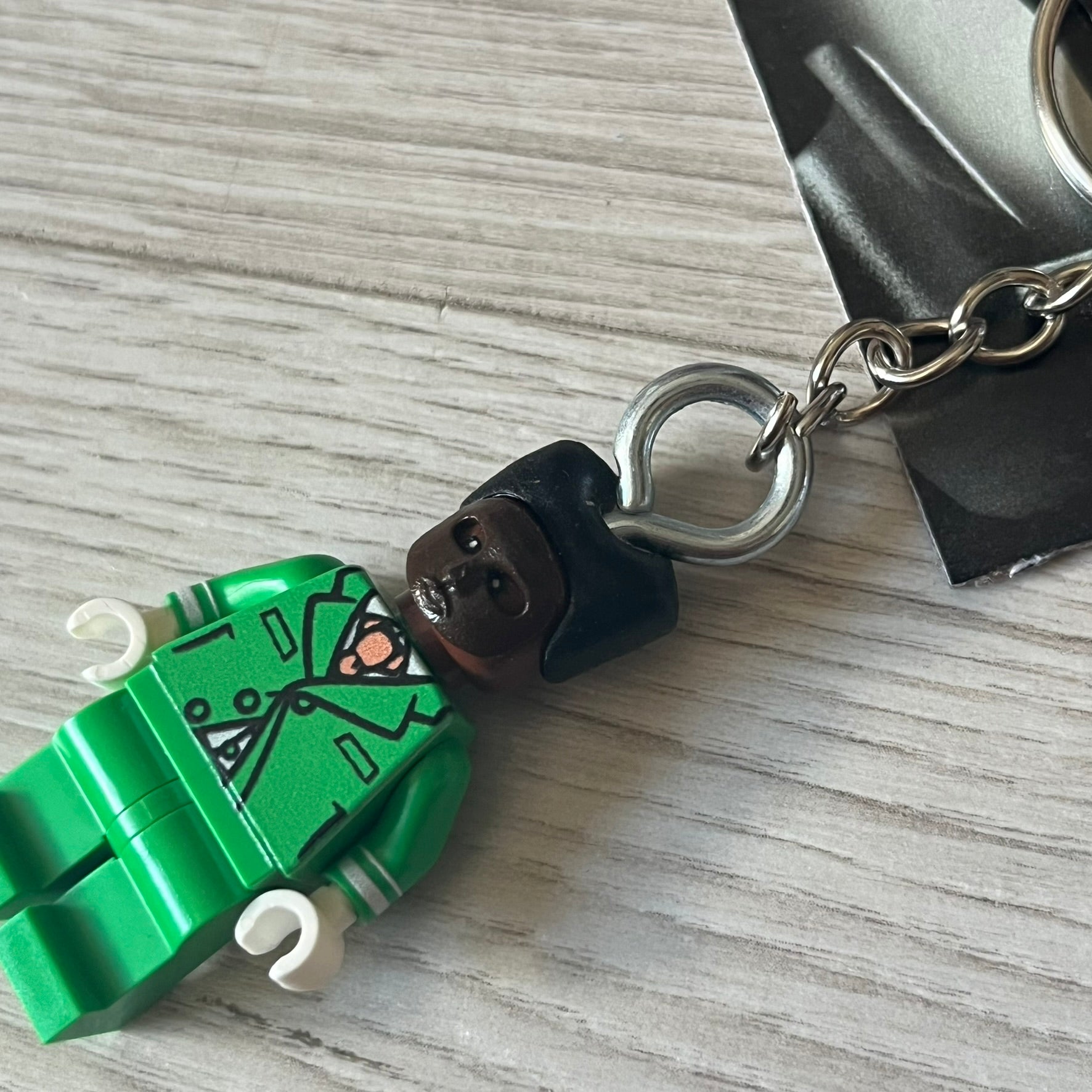 Lego x Tyler, the Creator “Brickakopia” keychain featuring a custom Lego figure of Tyler in a green suit. The figure is attached to a Lego-style recreation of the 2024 Chromakopia album cover, reimagined in brick graphics. A playful and creative collectible that merges music culture with fan-made Lego artistry, made by TheCanvasDon.