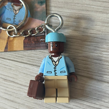Lego x Tyler, the Creator “Call Me If You Get Block” keychain featuring a custom Lego figure of Tyler in a blue jacket with matching ushanka and suitcase. The figure is mounted on a Lego-style recreation of the 2021 Call Me If You Get Lost album cover, reimagined entirely in brick graphics. A unique collectible that blends music culture with playful Lego-inspired design, made by TheCanvasDon.