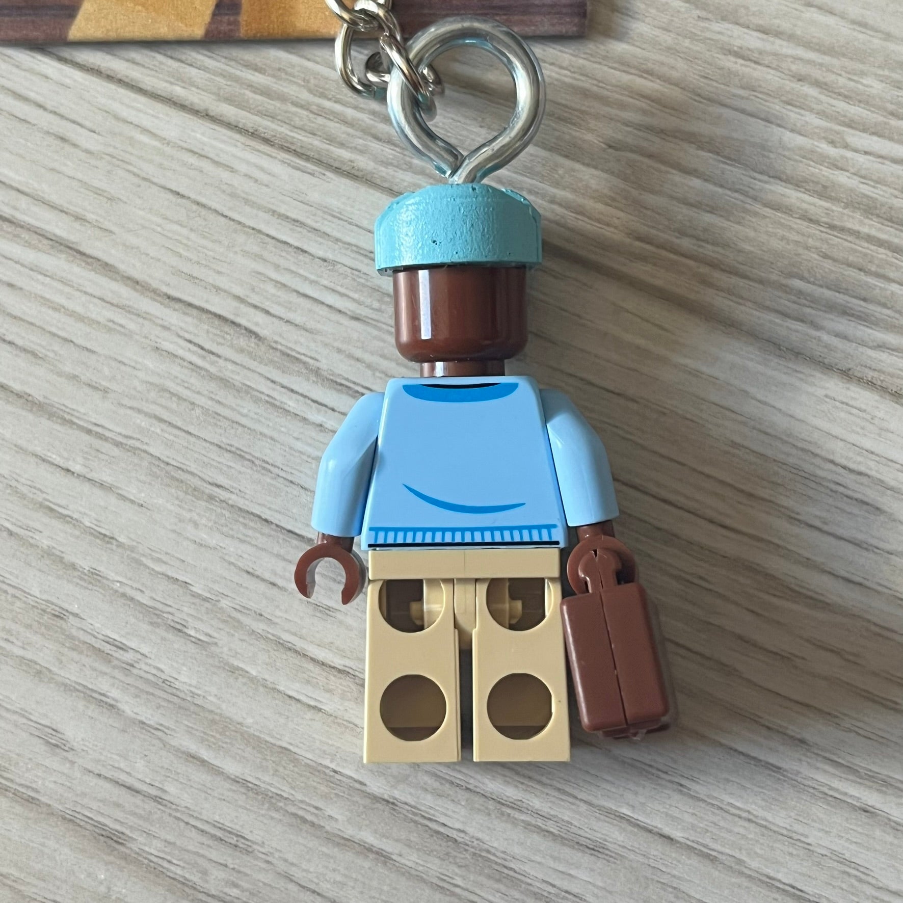 Lego x Tyler, the Creator “Call Me If You Get Block” keychain featuring a custom Lego figure of Tyler in a blue jacket with matching ushanka and suitcase. The figure is mounted on a Lego-style recreation of the 2021 Call Me If You Get Lost album cover, reimagined entirely in brick graphics. A unique collectible that blends music culture with playful Lego-inspired design, made by TheCanvasDon.