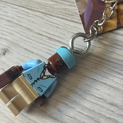 Lego x Tyler, the Creator “Call Me If You Get Block” keychain featuring a custom Lego figure of Tyler in a blue jacket with matching ushanka and suitcase. The figure is mounted on a Lego-style recreation of the 2021 Call Me If You Get Lost album cover, reimagined entirely in brick graphics. A unique collectible that blends music culture with playful Lego-inspired design, made by TheCanvasDon.