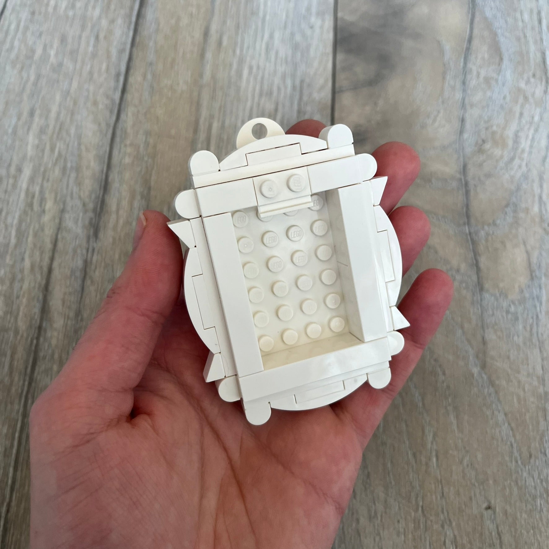 LEGO White Frame Make and Take Build is a limited promotional LEGO set distributed as an exclusive “make & take” event and not available for retail purchase. The model features a fully white 3D frame styled like a picture frame, designed for use as a photo holder. The back includes a hole for hanging or display.